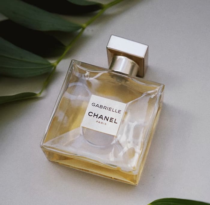Bottle of Gabrielle CHANEL perfume with green leaves in the background